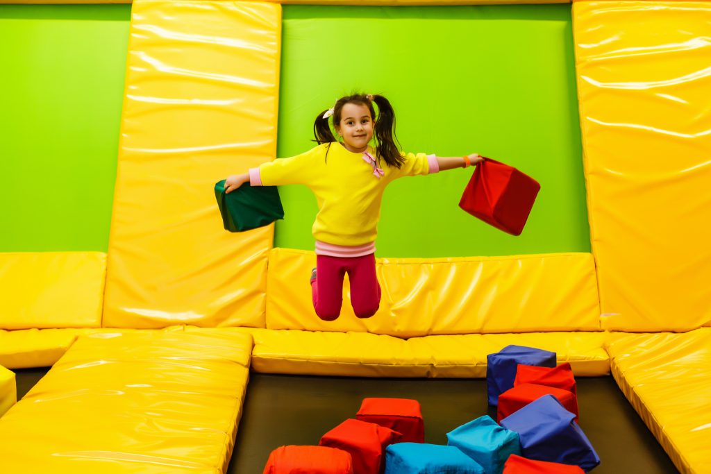 happy childhood of a modern child in the city - girl jumping in the trampoline park