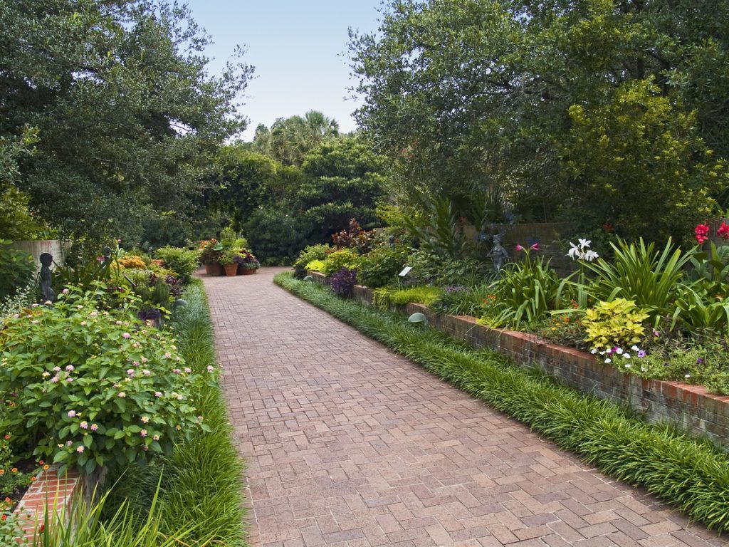 a brick pathway at Brookgreen Gardens with lush floral arrangements